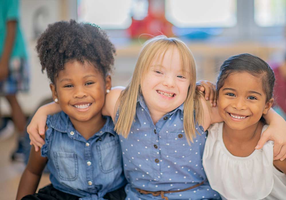 A group of young friends smile arm in arm at the camera