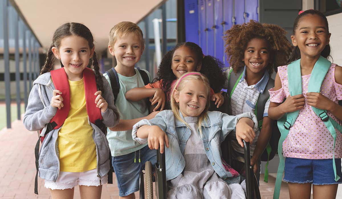 A group of smiling elementary age children smile at the camera