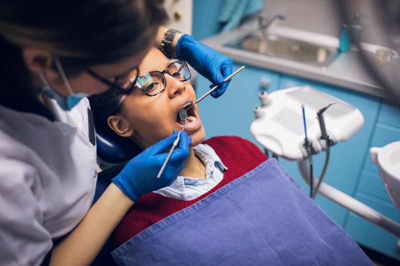 Smiling man in white lab coat and gloves looks at the camera - he's most likely a dentist